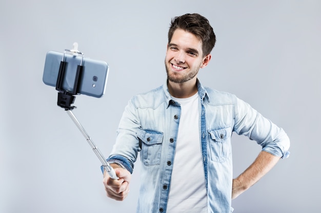 Hübscher junger Mann, der ein selfie über grauem Hintergrund nimmt.