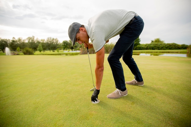 Hübscher junger Mann, der Golf spielt