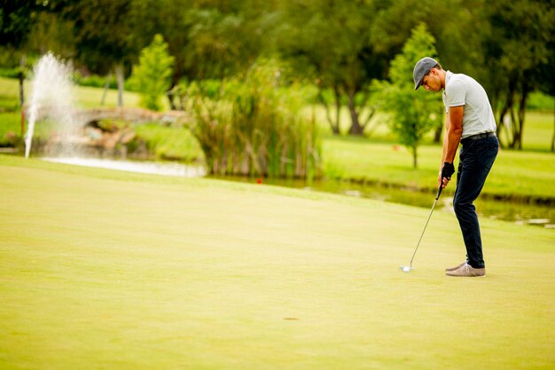 Hübscher junger Mann, der Golf spielt