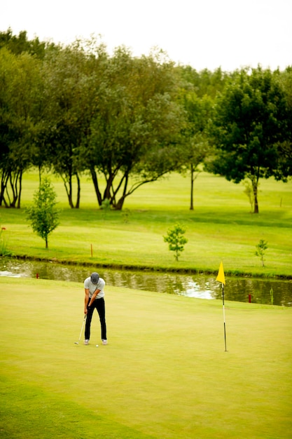 Hübscher junger Mann, der Golf spielt