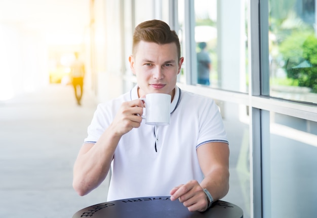 Hübscher junger Mann, der Kaffee in einem Café sitzt und trinkt