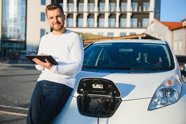 Hübscher junger Mann, der sein Auto auflädt