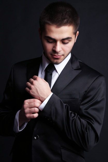 Hübscher junger Mann im Anzug auf dunklem Hintergrund