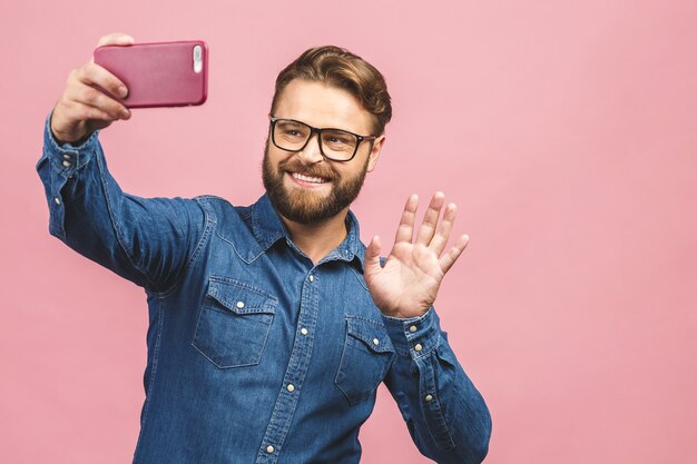 Hübscher junger Mann im Hemd, das Kamera hält und Selfie macht