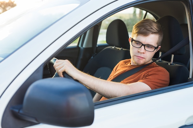 Hübscher junger Mann in einem braunen T-Shirt, das ein Auto fährt.