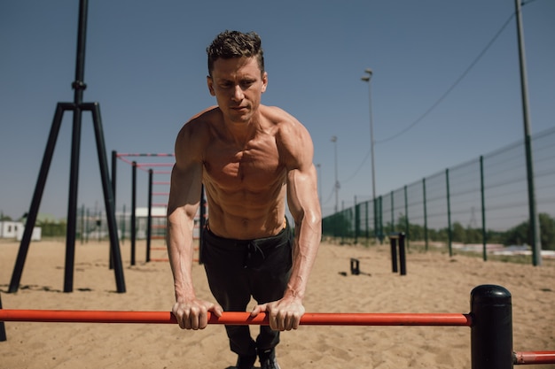 Hübscher junger Mann macht Street Workout am Strand an einem hellen Sommertag hochwertiges Foto