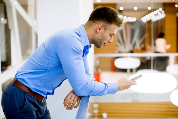 Hübscher junger Mann mit Handy im Büro