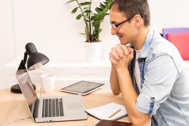 Hübscher junger Mann online mit einem Laptop