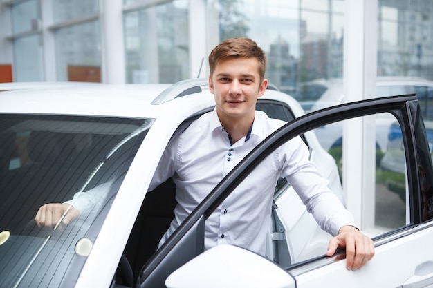 Hübscher junger Mann steigt beim Autohaus Cauto aus dem neuen Auto