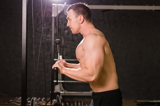Hübscher junger muskulöser Mann, der im Fitnessstudio trainiert