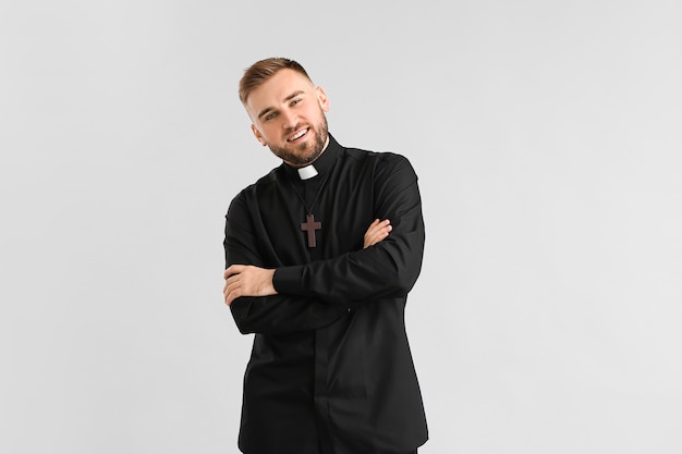 Hübscher junger Priester auf Grau