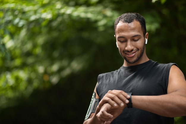 Hübscher junger schwarzer Sportler stellte seinen Fitness-Tracker ein