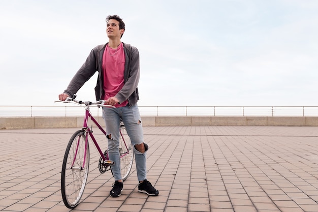 Hübscher junger Student, der ein Vintage-Fahrrad hält