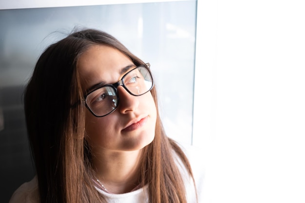 Foto hübscher junger student mit langen braunen haaren mit ernstem, nachdenklichem ausdruck auf hellem hintergrund