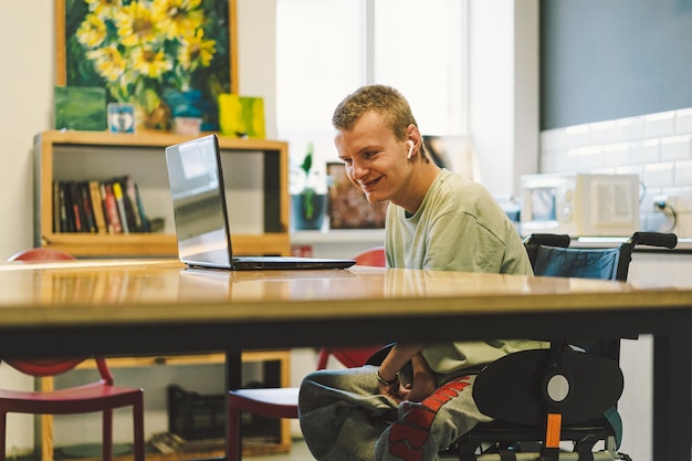 Hübscher junger ungültiger behinderter Mann, der auf dem Handy in der Küche spricht Person mit Behinderungen Video-Chat oder Anruf Porträt eines Menschen mit Behinderungen Optimistisch lächelnder behinderter Mann