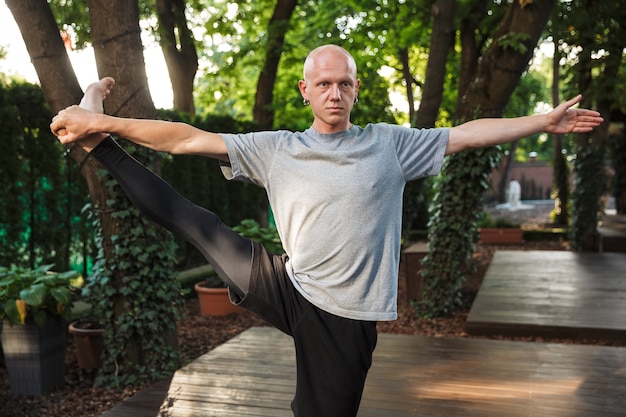 hübscher junger Yoga-Mann macht Dehnübungen im Freien.