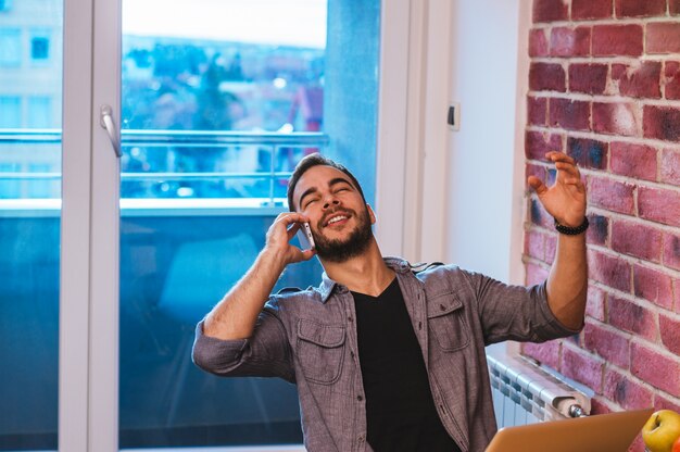 Foto hübscher kerl, der am telefon, gute nachrichten hörend spricht