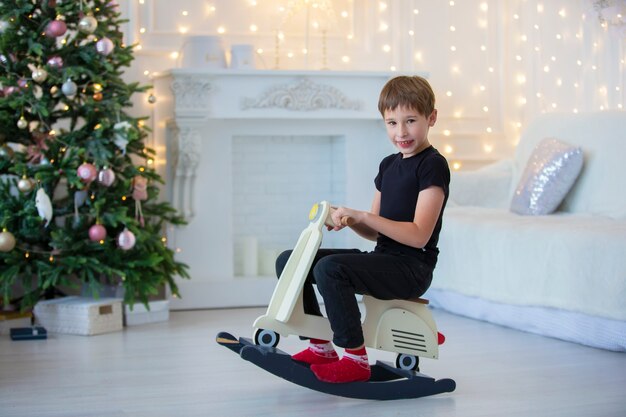 Hübscher kleiner Junge in Freizeitkleidung spielt im Weihnachtszimmer.