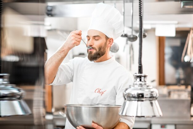 Hübscher Koch kocht Verkostung mit Löffelessen in der schönen Restaurantküche