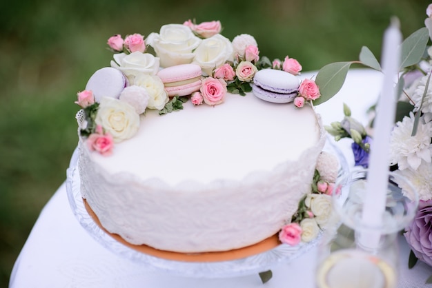 Hübscher Kuchen mit Makronen und Rosen steht auf dem Tisch