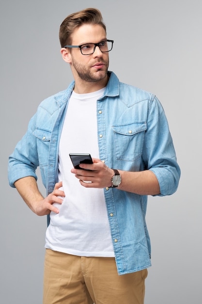 hübscher lässiger Mann im blauen Jeanshemd, der sein Telefon hält