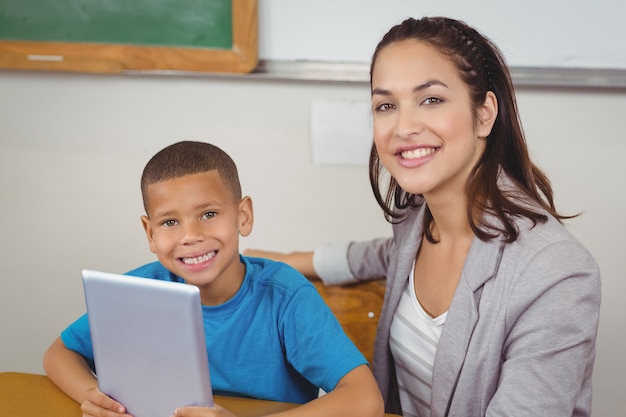 Hübscher Lehrer und Schüler mit Tablette an seinem Schreibtisch