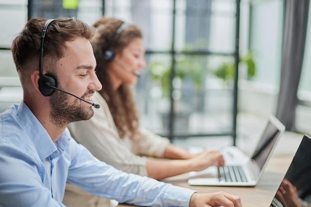 Foto hübscher männlicher kundendienstmitarbeiter, der im callcenter-büro als telemarketer arbeitet