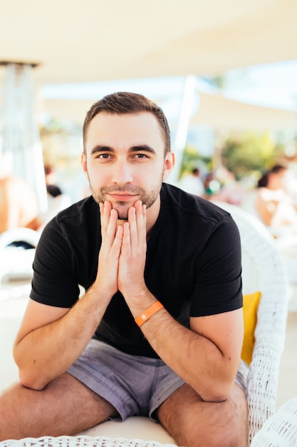 Hübscher Mann, der am Strandstrandrestaurant ruht. .