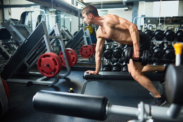 Hübscher Mann, der Muskeln im Fitnessstudio aufbaut