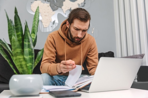 Foto hübscher mann, der zu hause arbeitet und durch ein notizbuch blättert