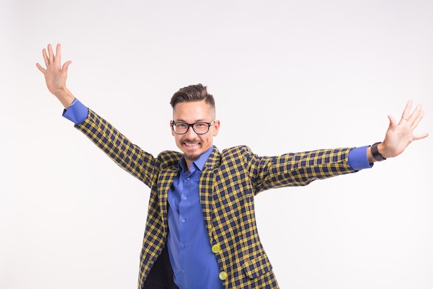 Foto hübscher mann in der jacke mit bart und schnurrbart in den gläsern, die spaß über weißer wand haben.