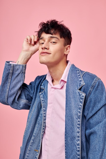 Hübscher Mann in der Jugend stilvolle Kleidung Jeansjacke posiert rosa Hintergrund unverändert