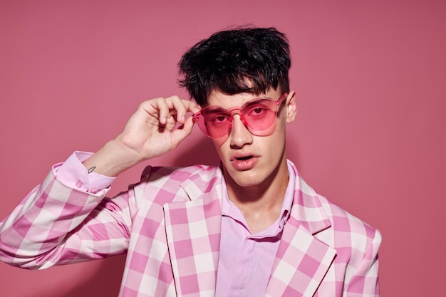 Hübscher Mann in rosa Brille rosa Blazer posiert Studio isoliert Hintergrund unverändert