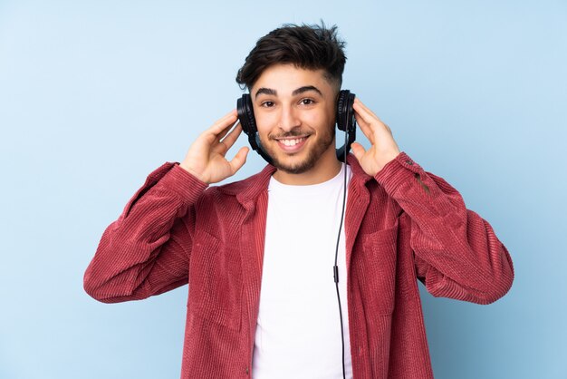 Hübscher Mann lokalisiert auf blauer Wand, die Musik hört