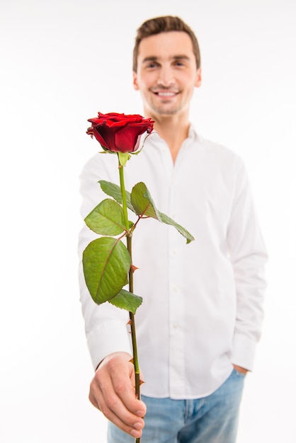 Hübscher mann mit einer roten rose, die hand in der tasche hält