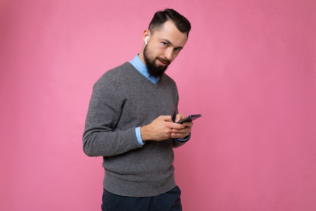 Hübscher Mann über rosa Hintergrund, der eine Nachricht mit dem Handy sendet