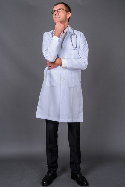 Hübscher Mannarzt mit kurzen Haaren gegen grauen Hintergrund