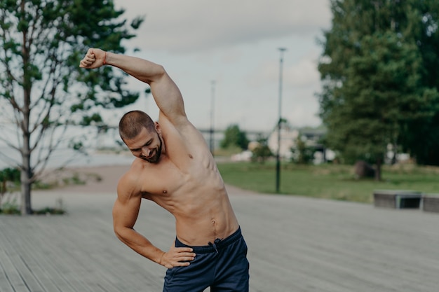 Hübscher muskulöser Mann mit nacktem Oberkörper im Freien, der Fitness-Training tut