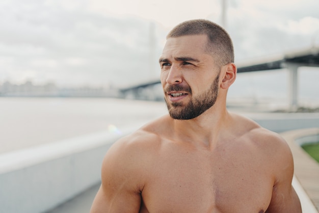 Hübscher muskulöser Mann mit nacktem Oberkörper im Freien, der Fitness-Training tut