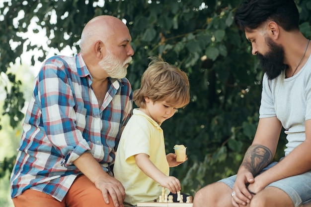 Hübscher Opa und Enkel spielen Schach, während sie Zeit miteinander im Freien verbringen