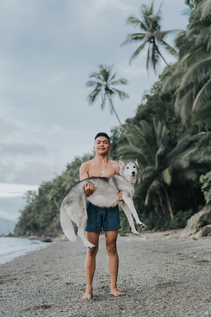 Hübscher philippinischer Teenager, der mit seinem sibirischen Husky-Haustier spielt