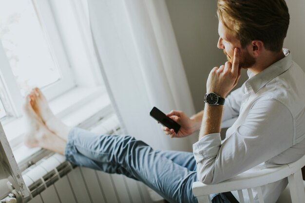 Hübscher redhair Mann schreibt eine Mitteilung am Telefon