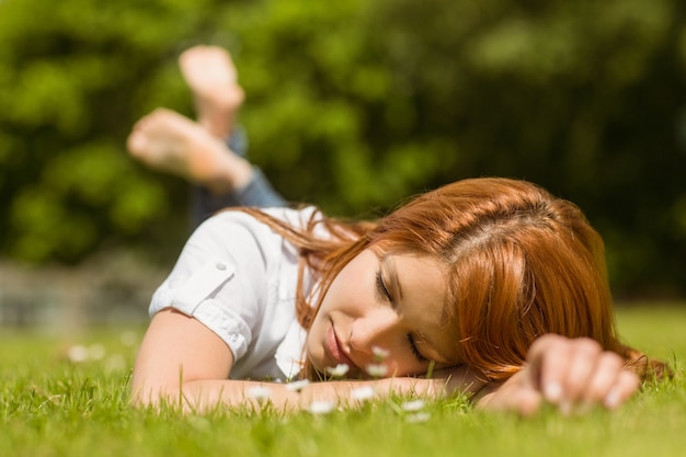 Foto hübscher redhead, der auf gras nickerchen macht