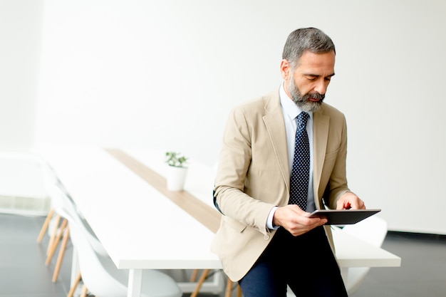 Hübscher reifer Geschäftsmann mit digitaler Tablette im Büro