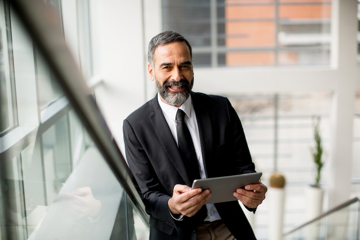 Foto hübscher reifer geschäftsmann mit tablette im büro