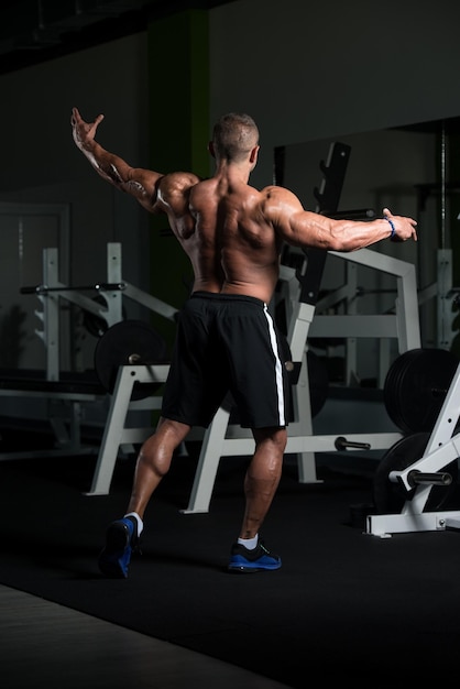 Hübscher reifer Mann, der stark in der Turnhalle steht und Muskeln muskulöser athletischer Bodybuilder-Eignungs-Mann aufwirft, der nach Übungen aufwirft