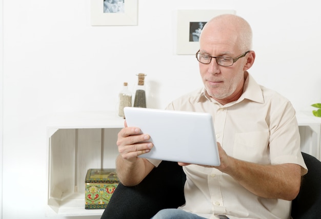 Hübscher reifer Mann, der Tablette verwendet