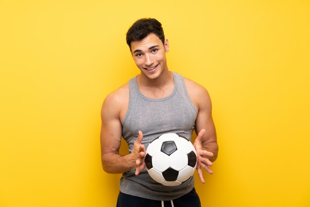 Hübscher Sportmann über lokalisierter Wand mit einem Fußball