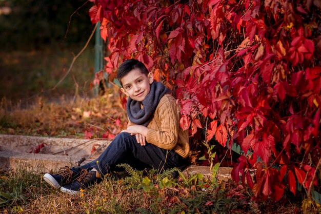 Hübscher stilvoller Junge, der in der Mode des Herbstparks steht