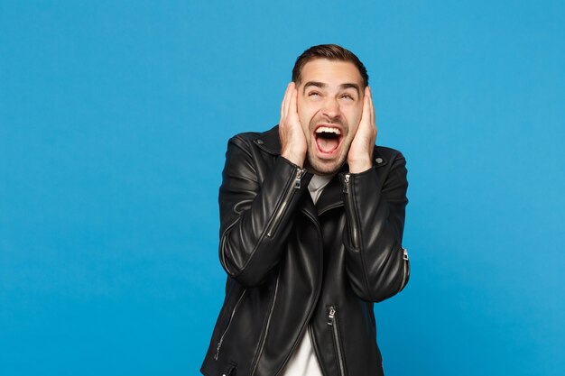 Hübscher, stilvoller junger, unrasierter Mann in schwarzer Lederjacke, weißem T-Shirt, der Kamera isoliert auf blauem Wandhintergrund-Studioporträt sieht. Menschen aufrichtige Emotionen Lifestyle-Konzept. Mock-up-Kopierraum